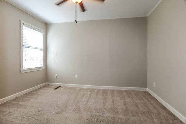 spare room with ceiling fan, baseboards, and light carpet