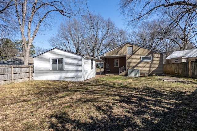 rear view of house featuring a lawn and a fenced backyard