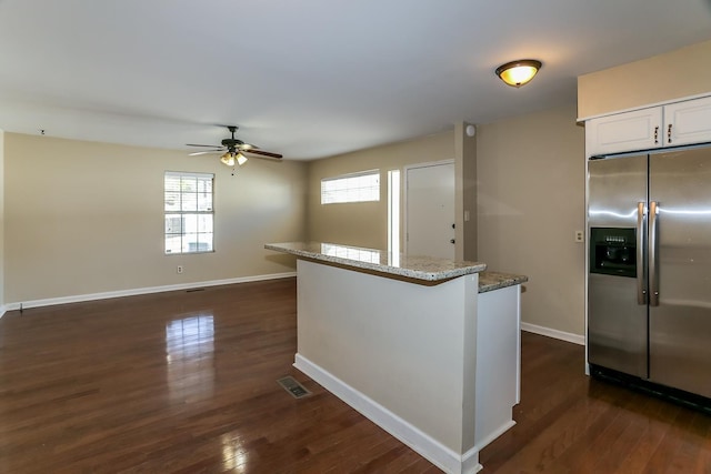 kitchen with dark wood finished floors, light stone countertops, stainless steel refrigerator with ice dispenser, and a wealth of natural light