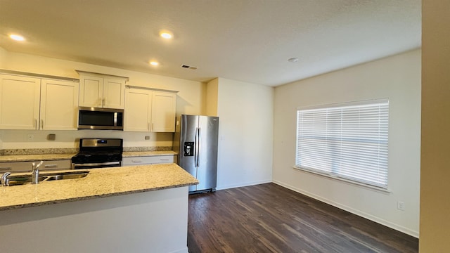 kitchen with stainless steel appliances, light stone countertops, baseboards, and dark wood-style floors