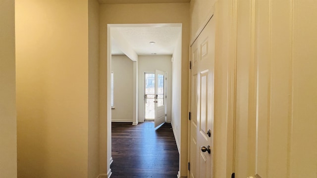 corridor featuring dark wood-style floors, baseboards, and a textured ceiling