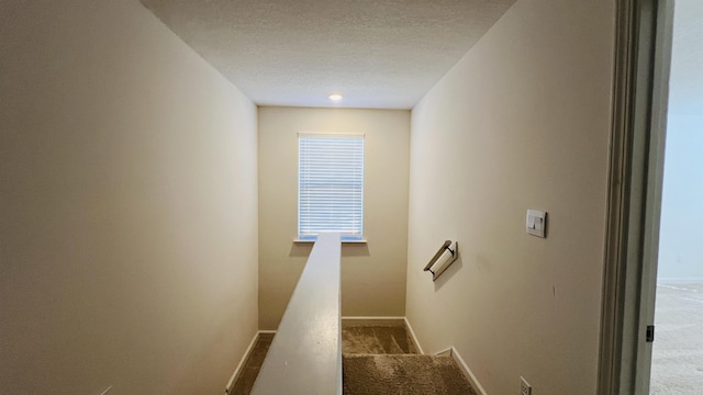 staircase with a textured ceiling, carpet, and baseboards