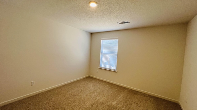 unfurnished room with visible vents, light carpet, a textured ceiling, and baseboards