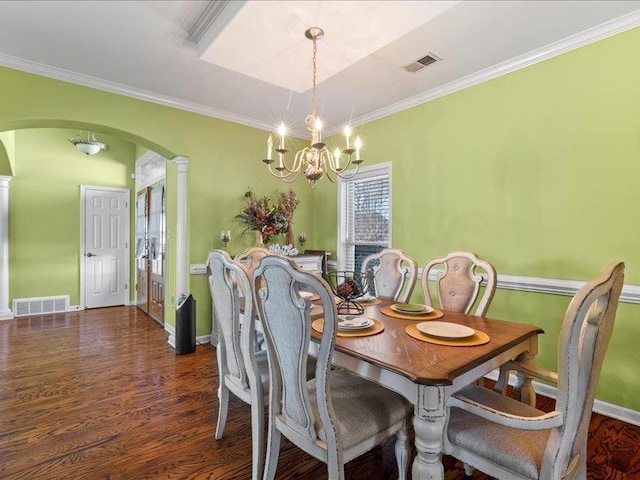 dining area with visible vents, ornamental molding, wood finished floors, arched walkways, and a chandelier