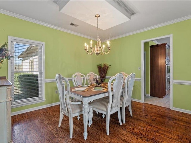 dining area featuring visible vents, baseboards, ornamental molding, wood finished floors, and a notable chandelier