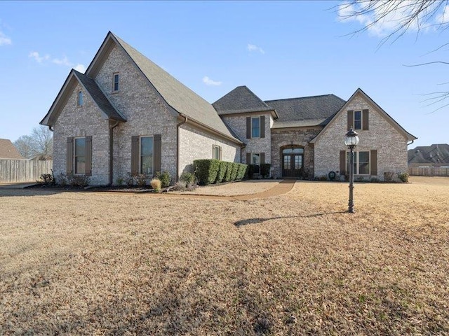 view of front of house featuring brick siding, french doors, and a front yard