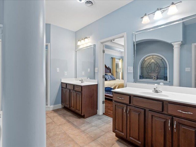 ensuite bathroom with visible vents, two vanities, ensuite bath, ornate columns, and a sink