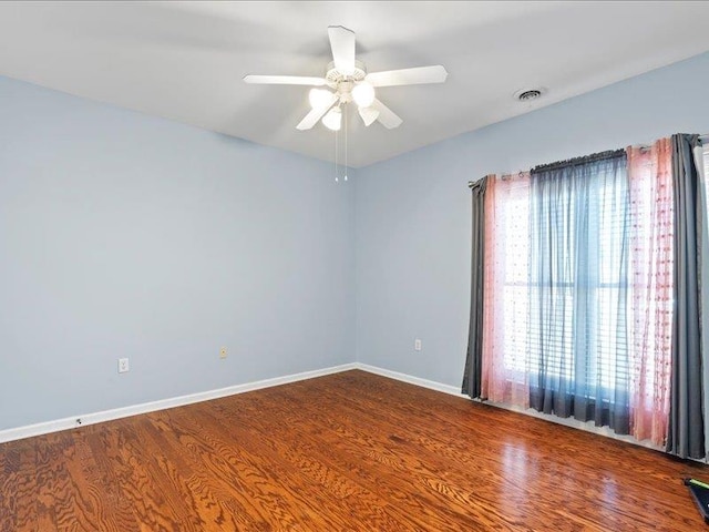 unfurnished room featuring a ceiling fan, wood finished floors, visible vents, and baseboards