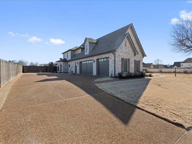 view of home's exterior featuring driveway, an attached garage, and fence