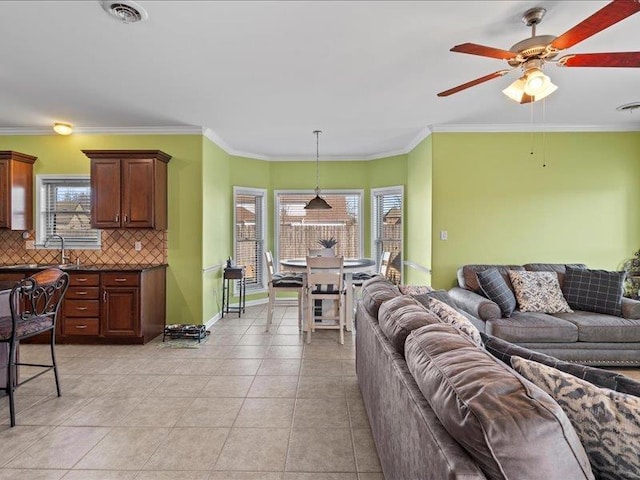 living room featuring a wealth of natural light, visible vents, ornamental molding, and light tile patterned floors