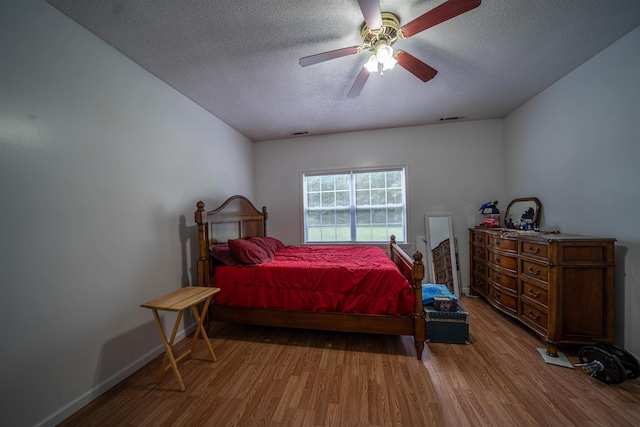 bedroom with visible vents, baseboards, a textured ceiling, and wood finished floors