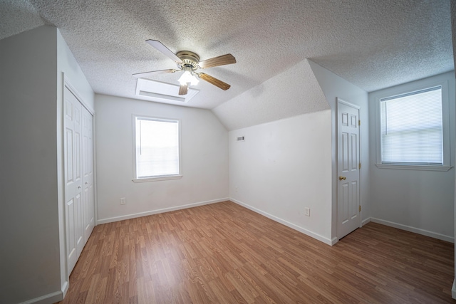 bonus room with a textured ceiling, wood finished floors, baseboards, ceiling fan, and vaulted ceiling