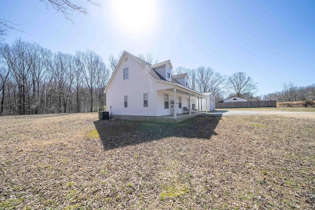 view of side of home featuring central air condition unit, fence, and covered porch