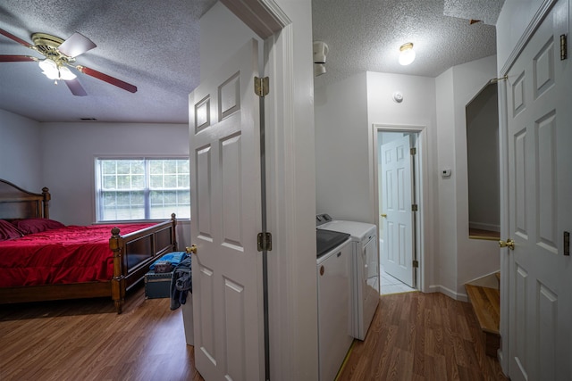 interior space featuring a textured ceiling, laundry area, wood finished floors, and washer and clothes dryer