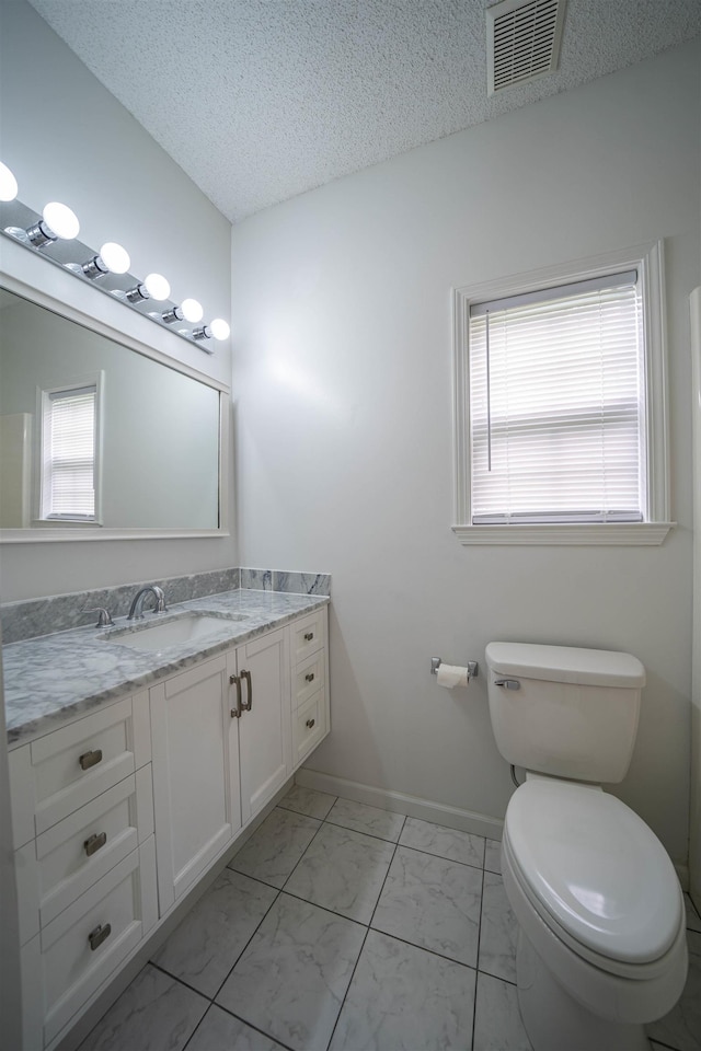 bathroom with visible vents, toilet, vanity, marble finish floor, and a textured ceiling