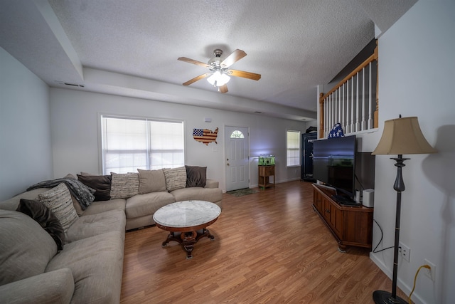 living area with light wood finished floors, visible vents, a textured ceiling, and a ceiling fan