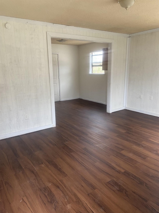 empty room featuring baseboards and dark wood-type flooring