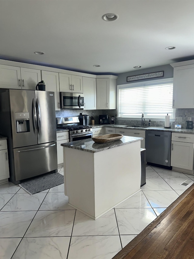 kitchen featuring a kitchen island, marble finish floor, stainless steel appliances, and a sink