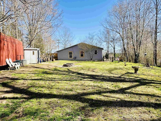 view of yard featuring fence, a storage shed, an outdoor structure, and an outdoor fire pit