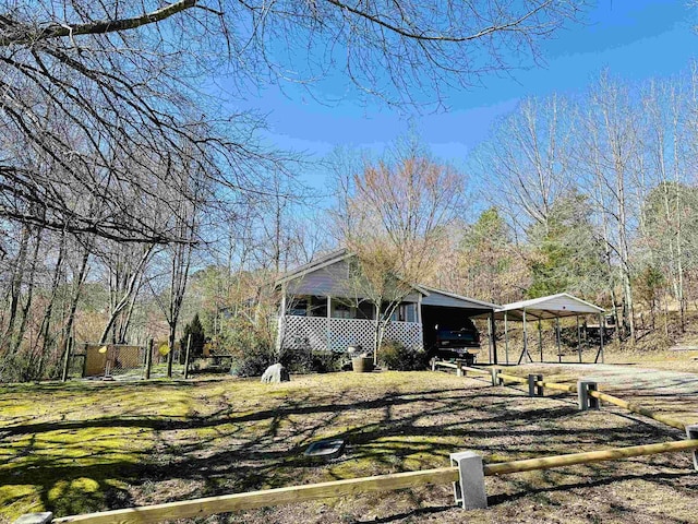 view of home's exterior with a yard, a detached carport, dirt driveway, and fence