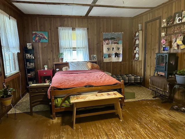 bedroom featuring wooden walls, wood finished floors, and a wood stove