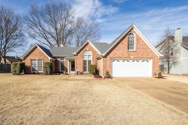 traditional-style house with a front lawn, fence, concrete driveway, a garage, and brick siding