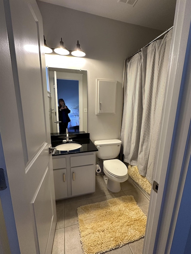 ensuite bathroom with tile patterned floors, toilet, curtained shower, and vanity