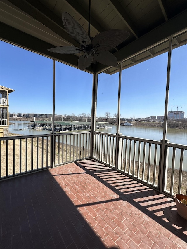 unfurnished sunroom with plenty of natural light, ceiling fan, and a water view