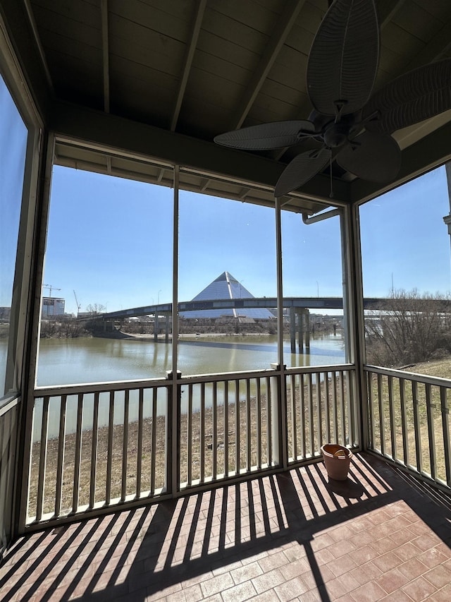 unfurnished sunroom featuring beam ceiling, a water view, a healthy amount of sunlight, and a ceiling fan