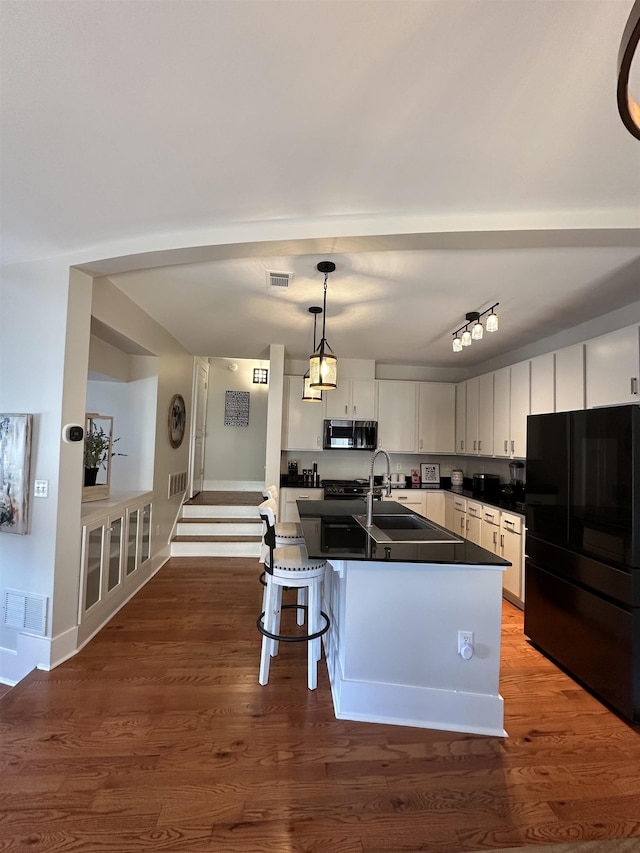 kitchen with stainless steel microwave, dark countertops, visible vents, and freestanding refrigerator