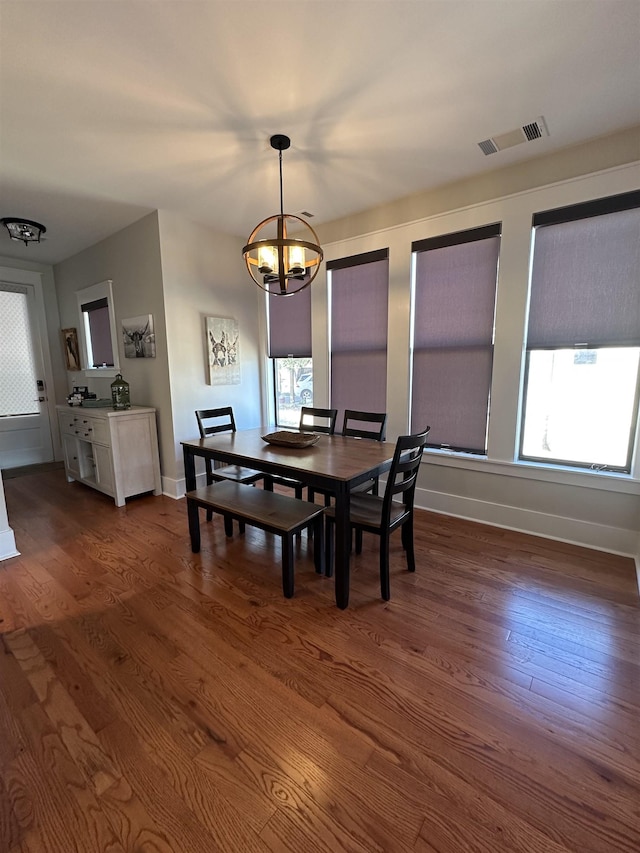 dining space with dark wood-style floors, a notable chandelier, baseboards, and visible vents