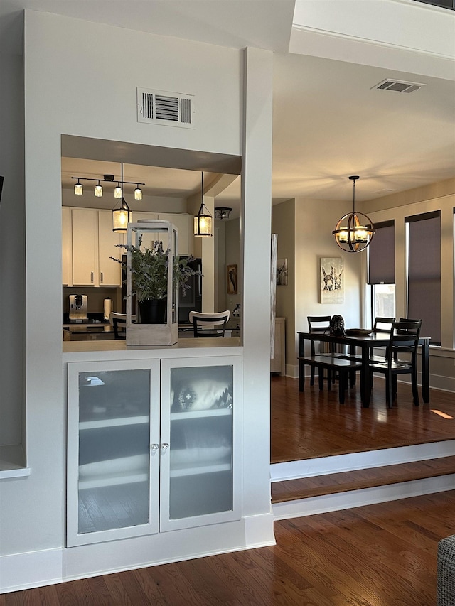 bar with dark wood-type flooring, baseboards, visible vents, and pendant lighting