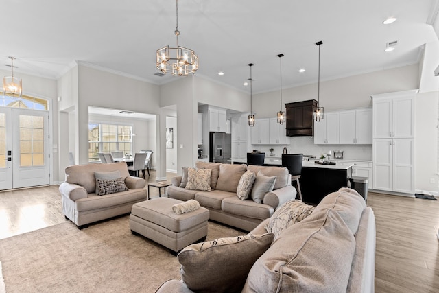 living area with light wood-style floors, a chandelier, and a towering ceiling