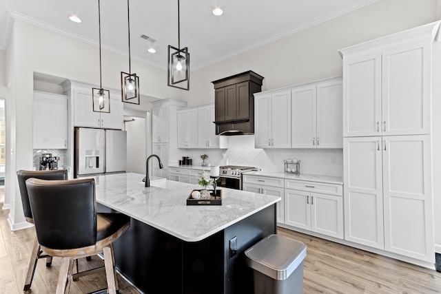 kitchen with gas stove, light wood-type flooring, crown molding, fridge with ice dispenser, and tasteful backsplash