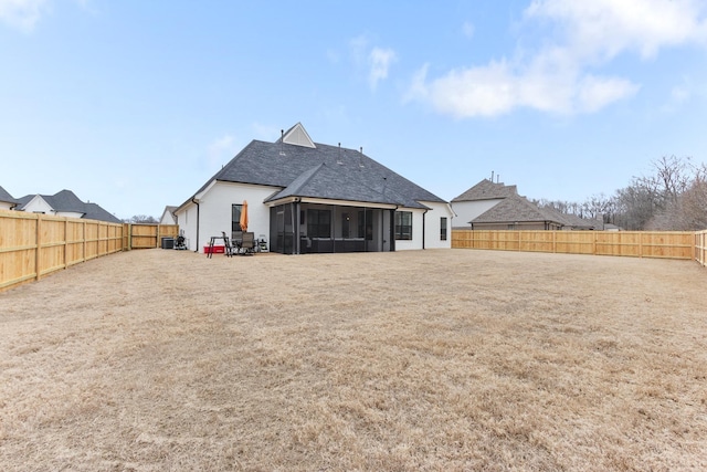 rear view of property featuring a lawn, a fenced backyard, and a sunroom