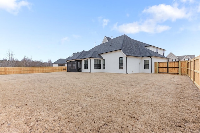 rear view of property featuring a fenced backyard and a sunroom