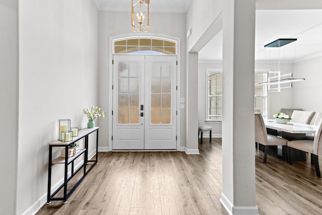 entrance foyer with baseboards, an inviting chandelier, wood finished floors, and ornamental molding