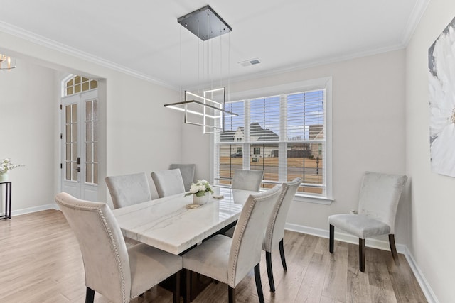 dining area with baseboards, a chandelier, ornamental molding, and light wood finished floors