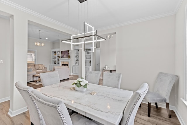 dining space featuring ornamental molding, wood finished floors, an inviting chandelier, a fireplace, and baseboards