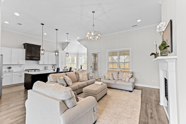 living area featuring visible vents, crown molding, light wood-type flooring, and baseboards