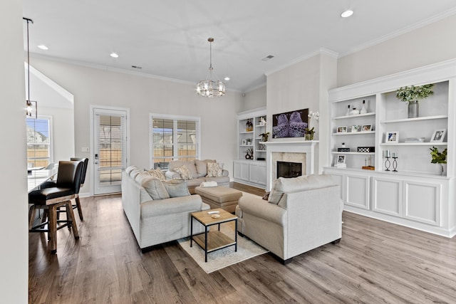 living room with wood finished floors, visible vents, an inviting chandelier, a fireplace, and recessed lighting