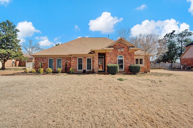 ranch-style house with brick siding, a shingled roof, and fence