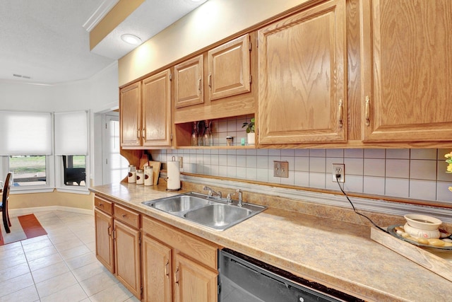 kitchen featuring a sink, backsplash, stainless steel dishwasher, light countertops, and light tile patterned floors