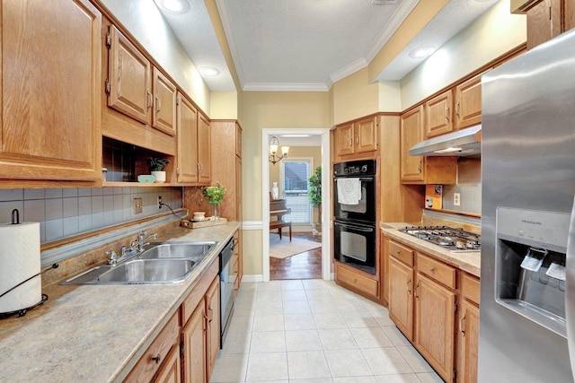 kitchen featuring crown molding, under cabinet range hood, light tile patterned floors, appliances with stainless steel finishes, and a sink