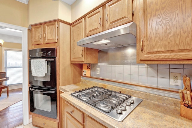 kitchen with backsplash, stainless steel gas cooktop, under cabinet range hood, and dobule oven black