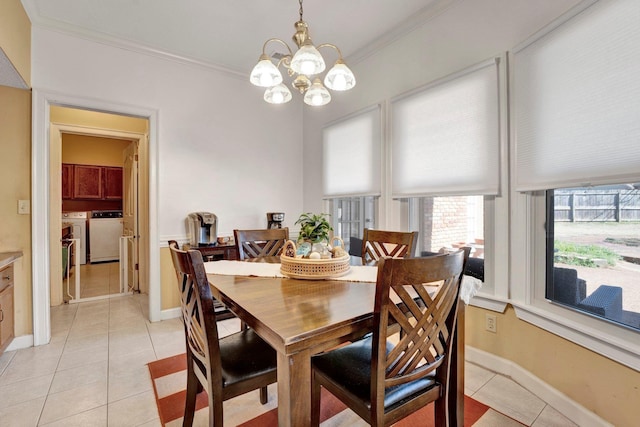 dining space featuring ornamental molding, light tile patterned flooring, a chandelier, and washing machine and clothes dryer