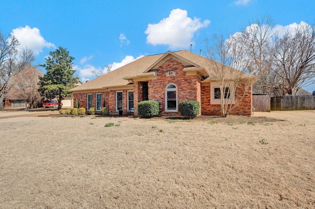 single story home featuring brick siding, a shingled roof, and fence