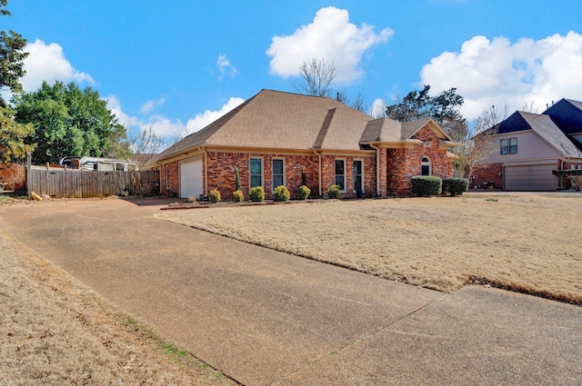 view of front of home with fence, roof with shingles, an attached garage, concrete driveway, and brick siding