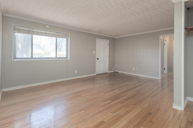 empty room with crown molding, light wood-style floors, and baseboards