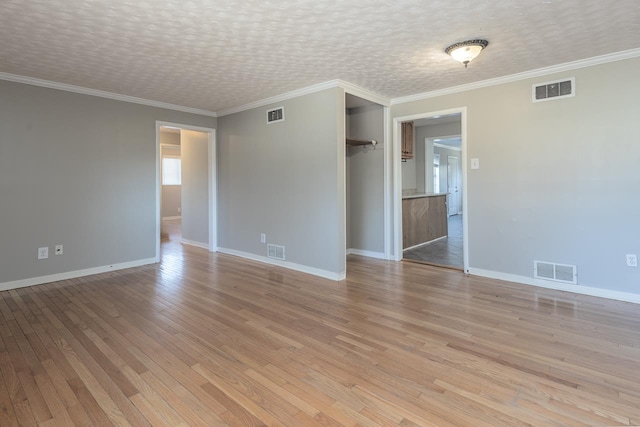 spare room featuring light wood-type flooring, visible vents, and a textured ceiling